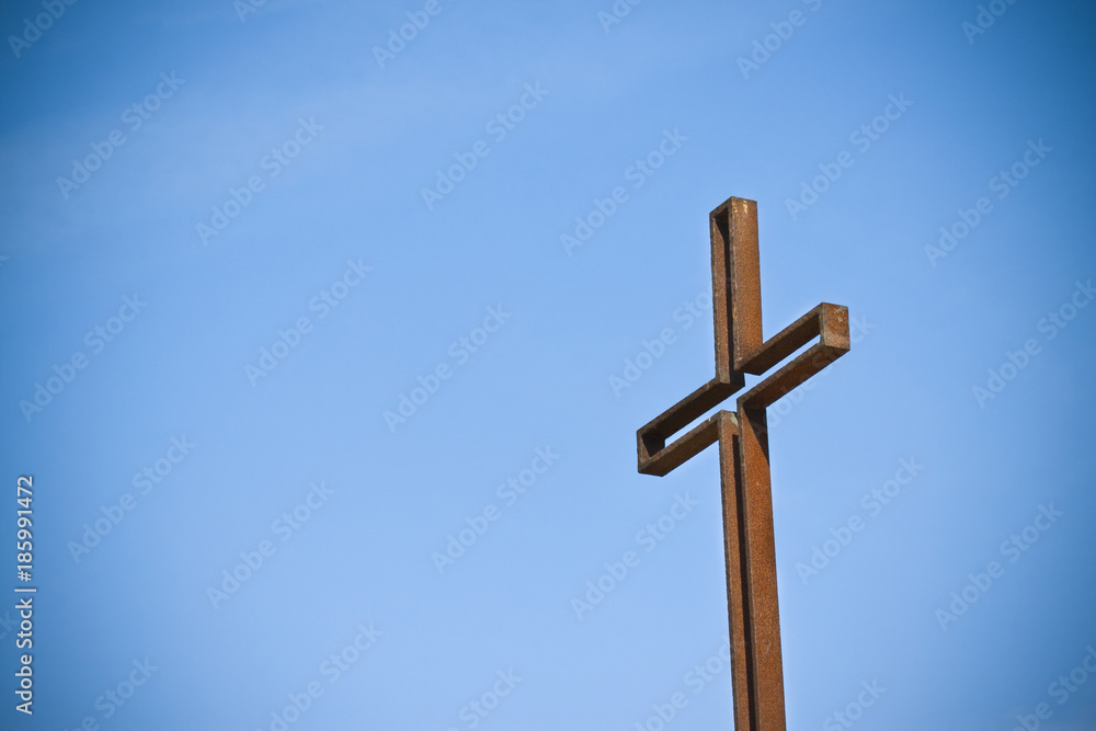 Rusty iron cross against a blue background - Image with copy space