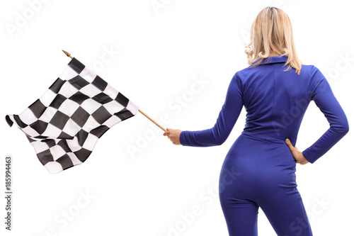 Rear shot of a woman in a racuing suit waving a checkered race flag