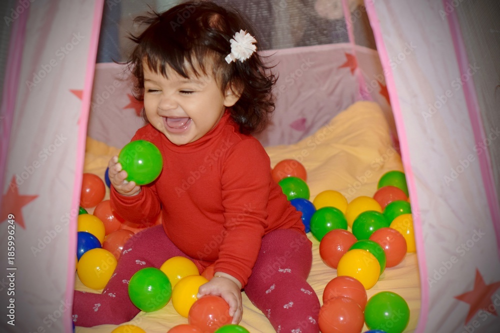 Obraz premium Happy little girl smiling and playing with balls
