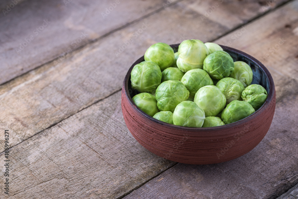 Brussels sprouts in ceramic bowl on rustic wooden table. Brussels sprouts in ceramic bowl on rustic wooden table.