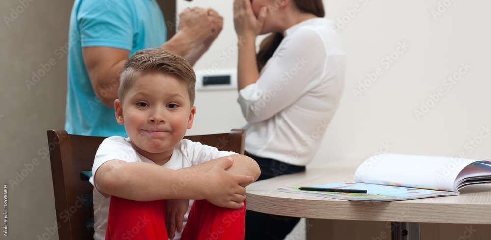 Small handsome boy against background of blurred parents - father abuses and beats frightened mother Small handsome boy against background of blurred parents - father abuses and beats frightened mother
