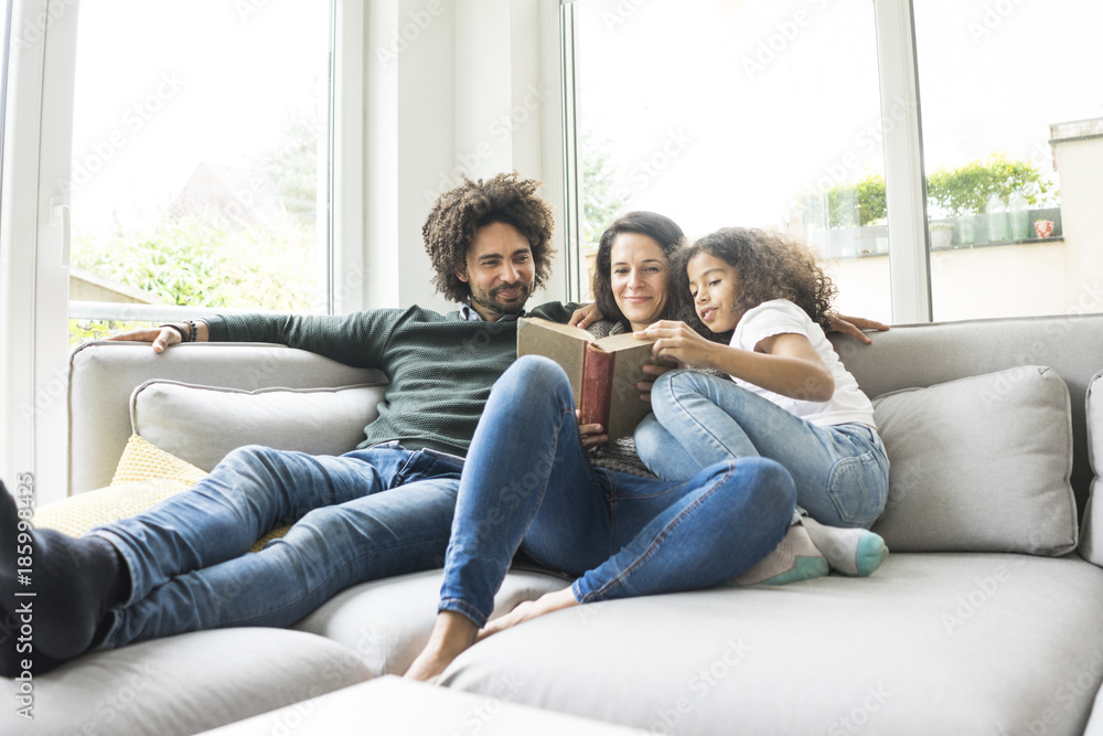 Happy family sitting on couch, reading book Happy family sitting on couch, reading book