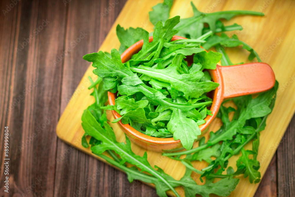 Fresh juicy leaves of arugula on a brown wooden table.