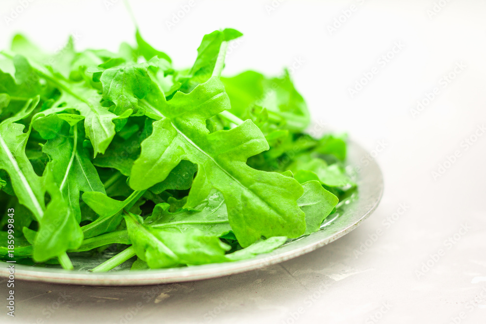 Fresh juicy leaves of arugula on a light concrete background. Fresh juicy leaves of arugula on a light concrete background.