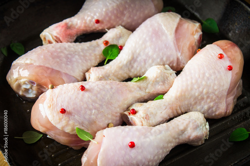 Raw chicken legs in a frying pan on a wooden table. Meat ingredients for cooking.