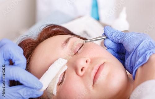 Surgeon applies a bandage to the female patient's eyelids after a blepharoplasty operation photo