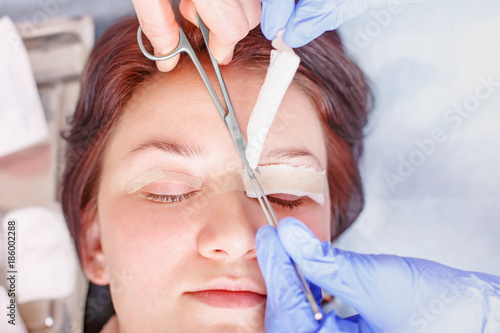 Surgeon applies a bandage to the female patient's eyelids after a blepharoplasty operation