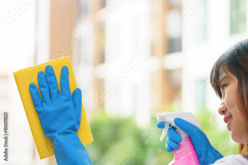 Woman housekeeper cleaning the mirror with yellow cloth.