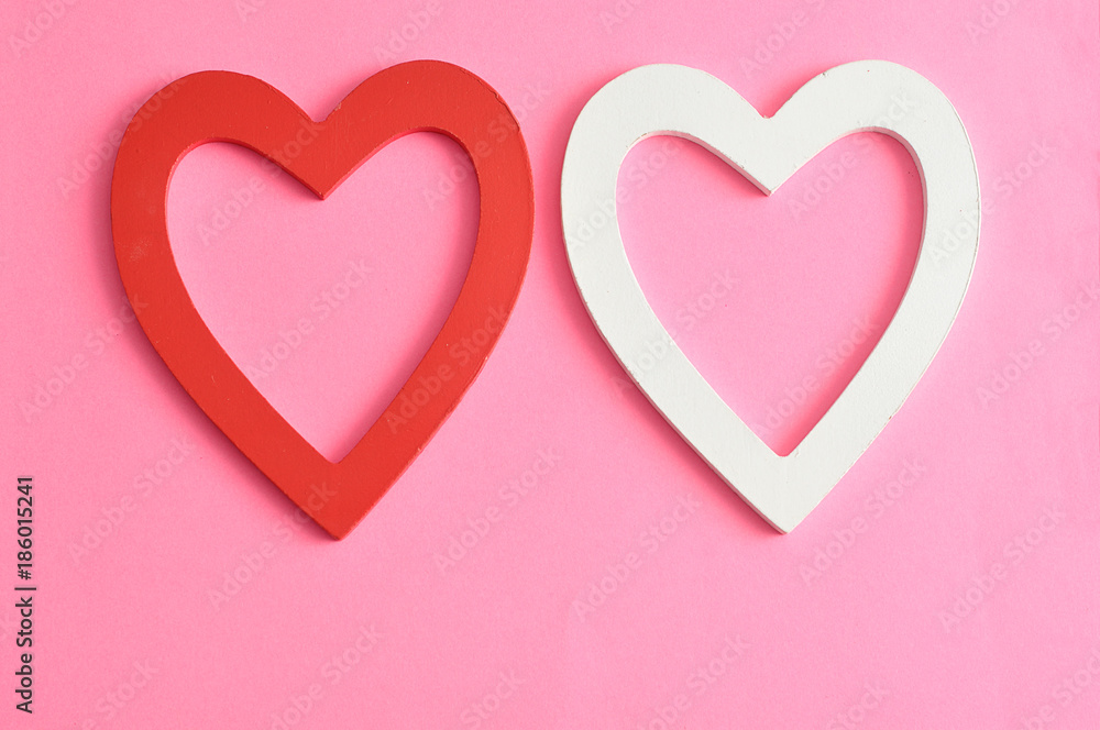 Valentine's Day. A red and white wooden hearts isolated against a pink background