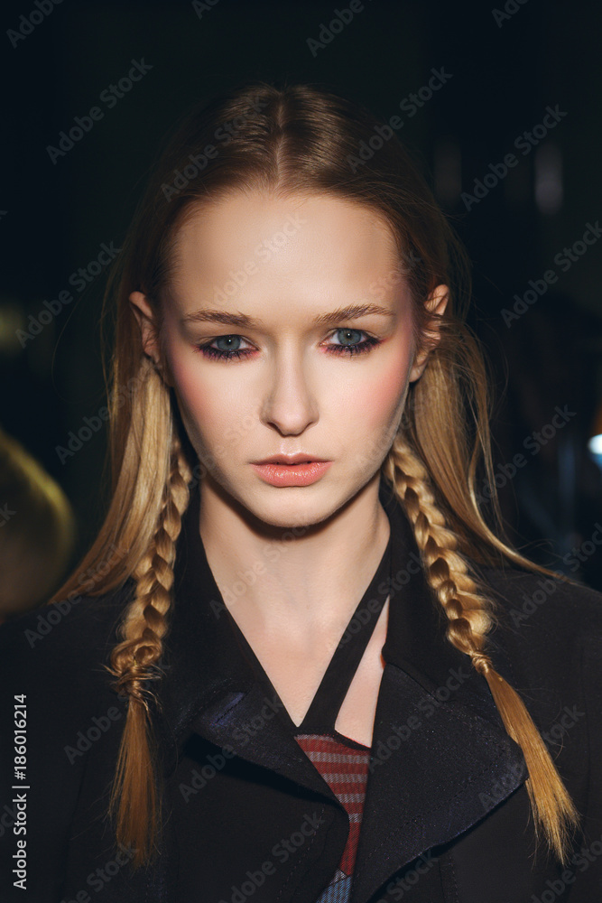 Close up portrait of hippie girl with pigtails in hair looking stern and wearing shabby coat Close up portrait of hippie girl with pigtails in hair looking stern and wearing shabby coat