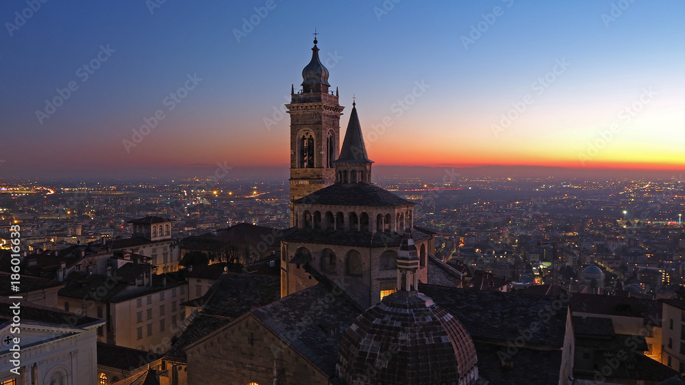 Bergamo, Italy. The old city. Aerial view of the Basilica of Santa Maria Maggiore and the chapel Colleoni during the sunset. In the background the Po plain