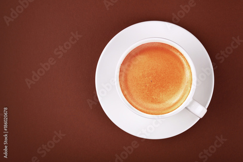 Full white cup of espresso coffee on brown