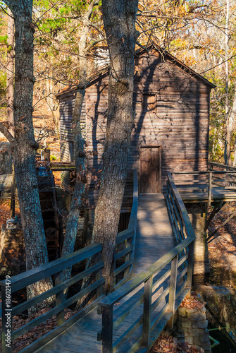 Grist Mill and the wooden bridge in the Stone Mountain Park in sunny autumn day, Georgia, USA
