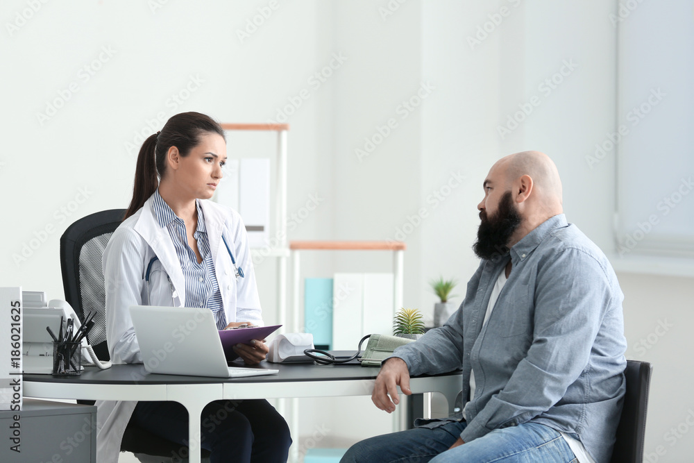 Young female doctor consulting overweight man in clinic Young female doctor consulting overweight man in clinic