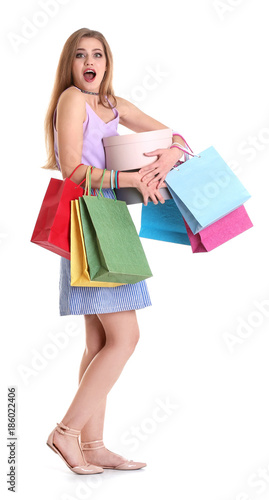 Excited young woman with shopping bags and boxes on white background