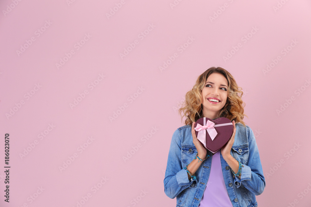 Attractive young woman with gift box on color background Attractive young woman with gift box on color background