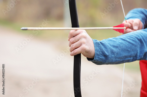 Hands of woman practicing archery outdoors