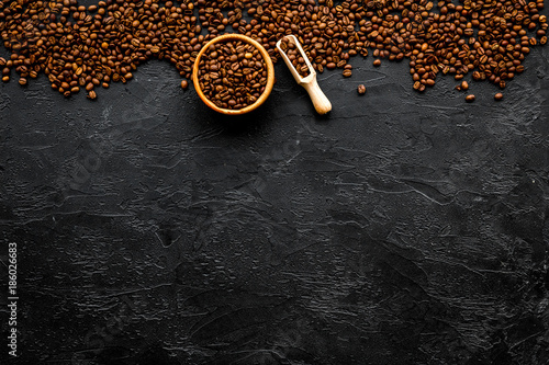 Coffee background. Roasted beans in bowl and scoop on black table top view copyspace