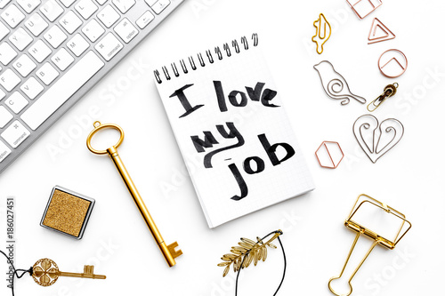 Happy at work. Handwritten motto I love my job in notebook near stationery on white background top view photo