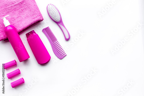 Basic hair care in bathroom. Comb, shampoo, spray, curlers, towel on white background top view copyspace