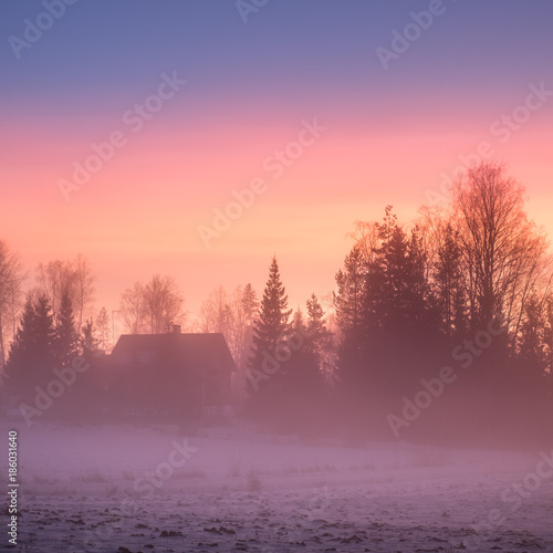 Foggy and colorful sunset with peaceful landscape at winter evening in Finland