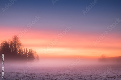 Foggy and colorful sunset with peaceful landscape at winter evening in Finland