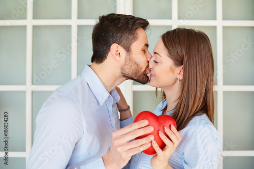 A loving couple with a red heart kissing. Valentine's Day.