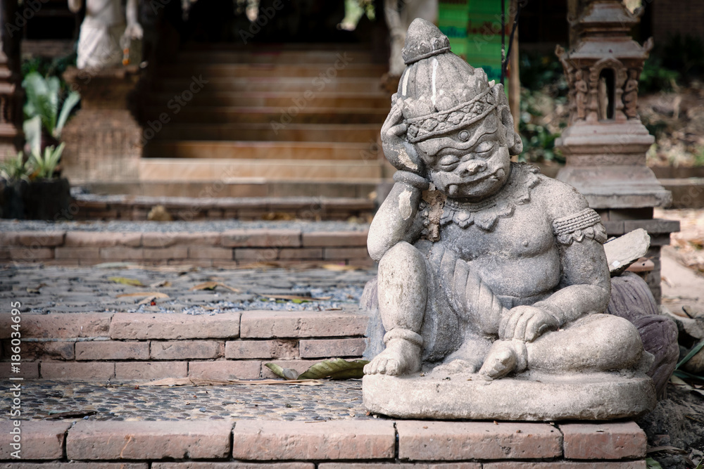 Statue of little, thinking demon in front of temple in Chiang Mai, Thailand