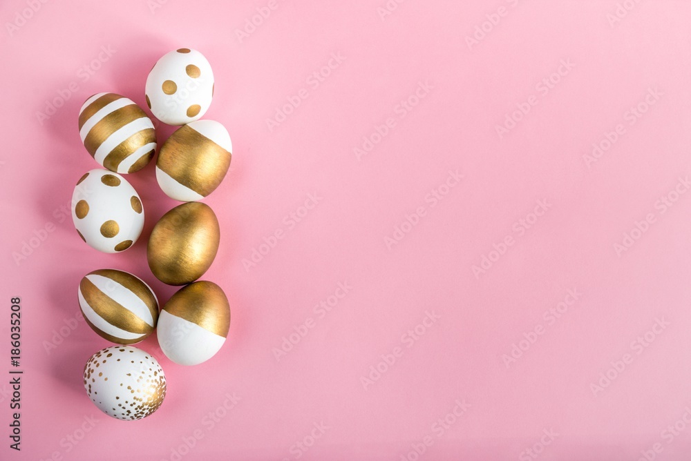 Top view of easter eggs colored with golden paint. Various striped and dotted designs. Pink background.