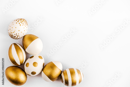 Top view of easter eggs colored with golden paint. Various striped and dotted designs. White background.