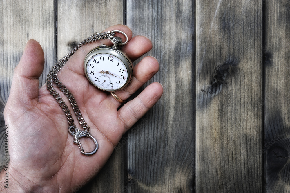 Adult man holding an antique pocket watch in his hand Adult man holding an antique pocket watch in his hand