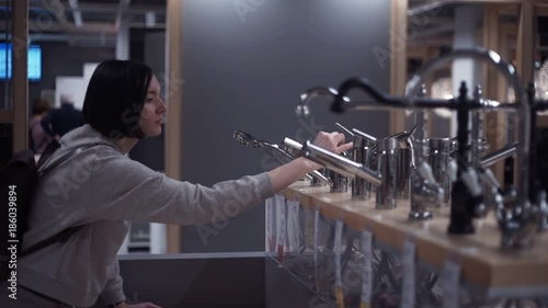 Young girl examining water faucet taps in furniture store