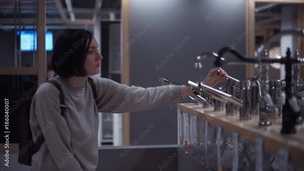 Young girl examining water faucet taps in furniture store Young girl examining water faucet taps in furniture store