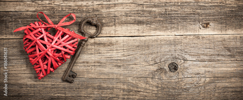 Red wicker heart and vintage key on wooden background