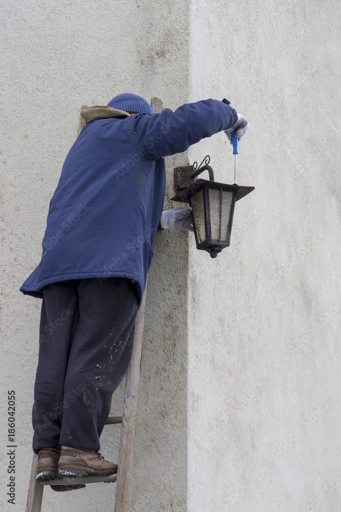 Man repairing lantern on a ladder
