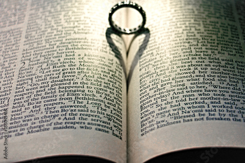 Wedding ring thrown heart shadow inside an open bible