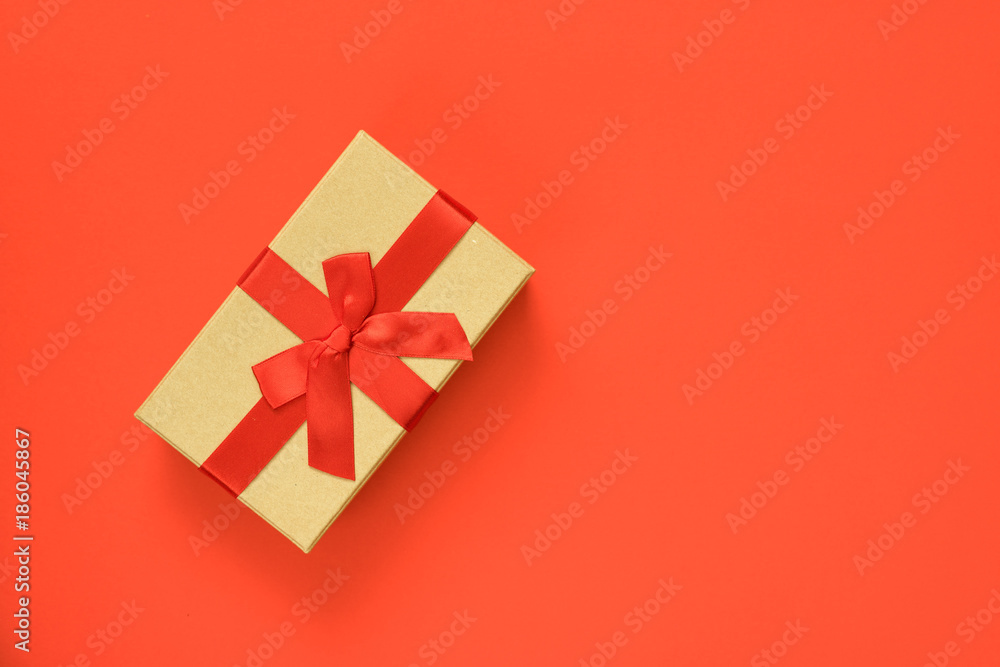 Gift box with red ribbon on red background. Close up. Top view.