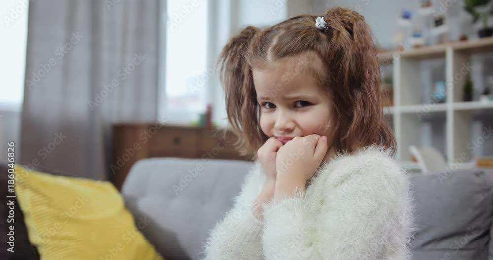 Portrait of a serious sad little girl sit on the sofa in home cute person upset sadness alone beautiful blond emotion face lifestyle looking pretty family child girl childhood close up slow motion Portrait of a serious sad little girl sit on the sofa in home cute person upset sadness alone beautiful blond emotion face lifestyle looking pretty family child girl childhood close up slow motion