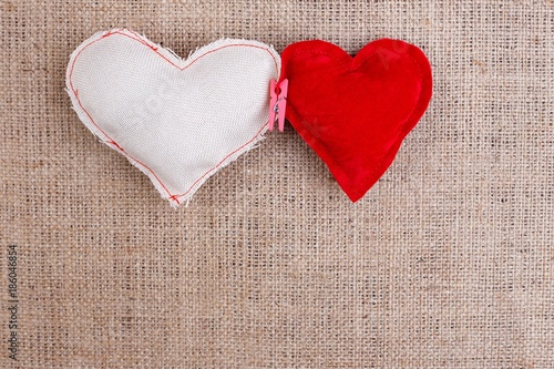 Two handmade fabric hearts clipped with clothespin on sackcloth  copy space. Valentine background  love concept