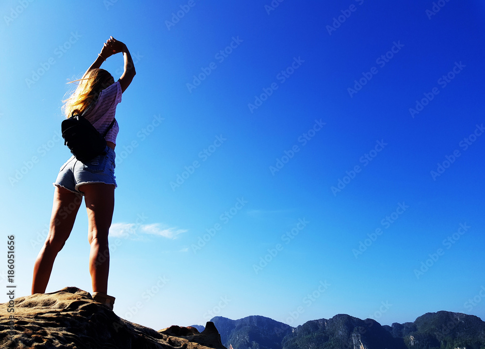 Silhouette woman standing on the top of mountain over blue sea and sky background Silhouette woman standing on the top of mountain over blue sea and sky background