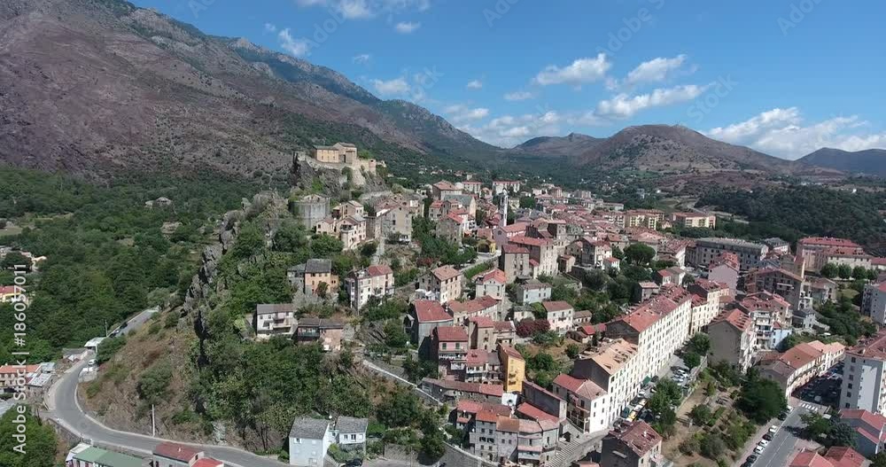 CORTE, CORSICA, FRANCE – JULY 2016 : Aerial shot of Corte cityscape on a sunny day with amazing landscape in view CORTE, CORSICA, FRANCE – JULY 2016 : Aerial shot of Corte cityscape on a sunny day with amazing landscape in view