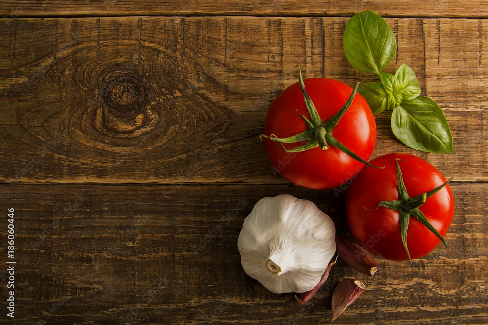 Vegetables on a wooden table, tomatoes and garlic head with a green basil. Vegetables on a wooden table, tomatoes and garlic head with a green basil.