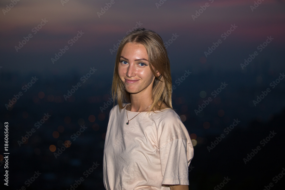 Portrait of young attractive caucasian woman during night with city background.