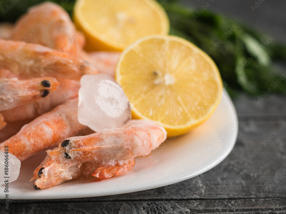 Pieces of ice from the frozen shrimp in a clay bowl on a dark wooden table. Pieces of ice from the frozen shrimp in a clay bowl on a dark wooden table.