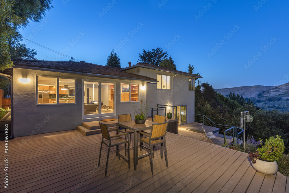 Wooden Deck outdoor patio at night with amazing hillside view and illuminated house.