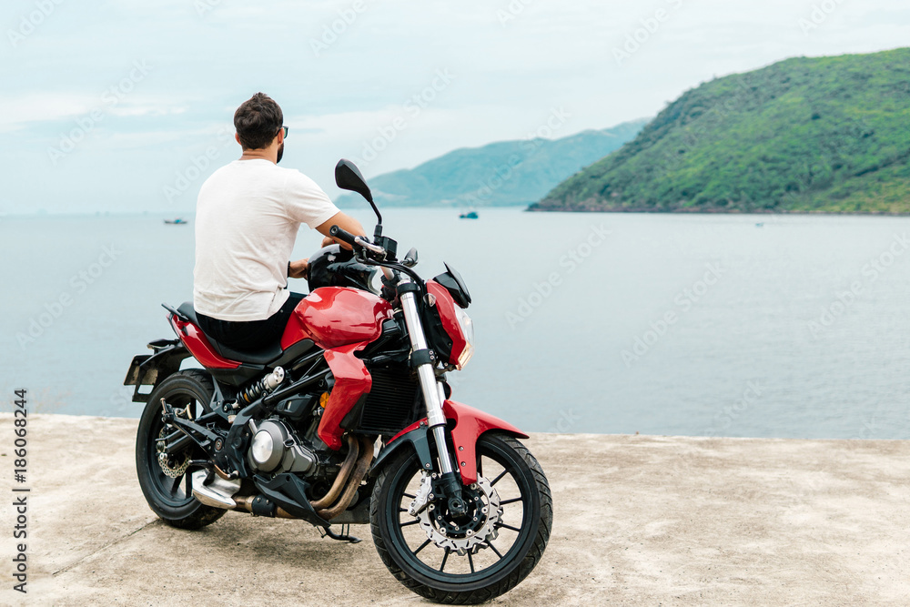 Man sitting on his motorcycle and looking at the sea