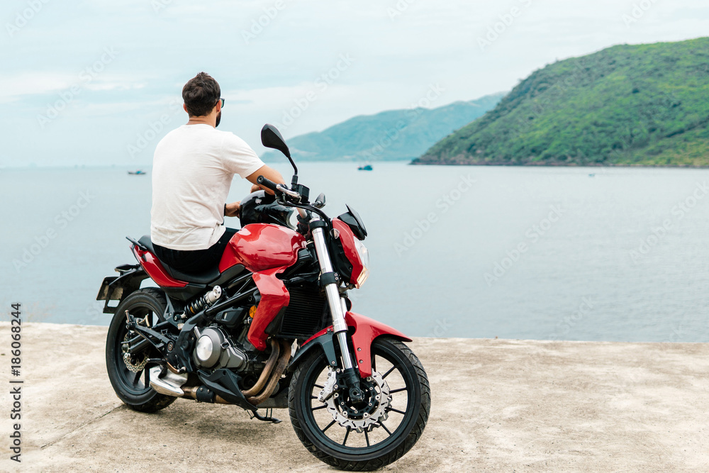 Man sitting on his motorcycle and looking at the sea Man sitting on his motorcycle and looking at the sea
