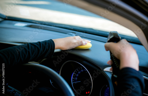 Hands woman worker cleaning car inside dashboard with waxy