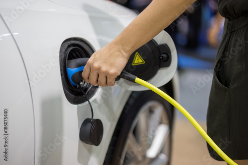 Hand holding Electric car charger. Power supply electric car charging for electric car technology transportation in the future.