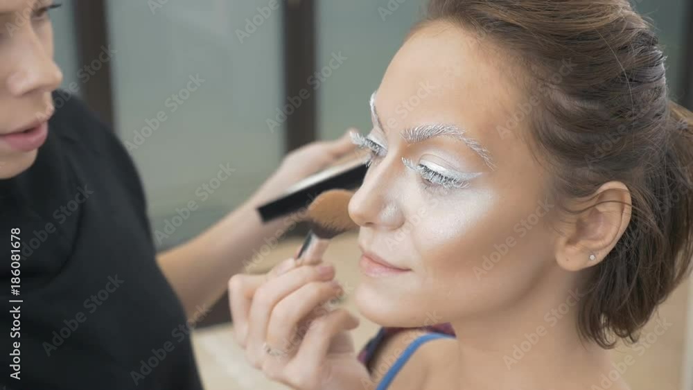 A professional make-up artist does the make-up of the model. Apply a special brush with a tonal paint. Preparation for an artistic photo shoot A professional make-up artist does the make-up of the model. Apply a special brush with a tonal paint. Preparation for an artistic photo shoot